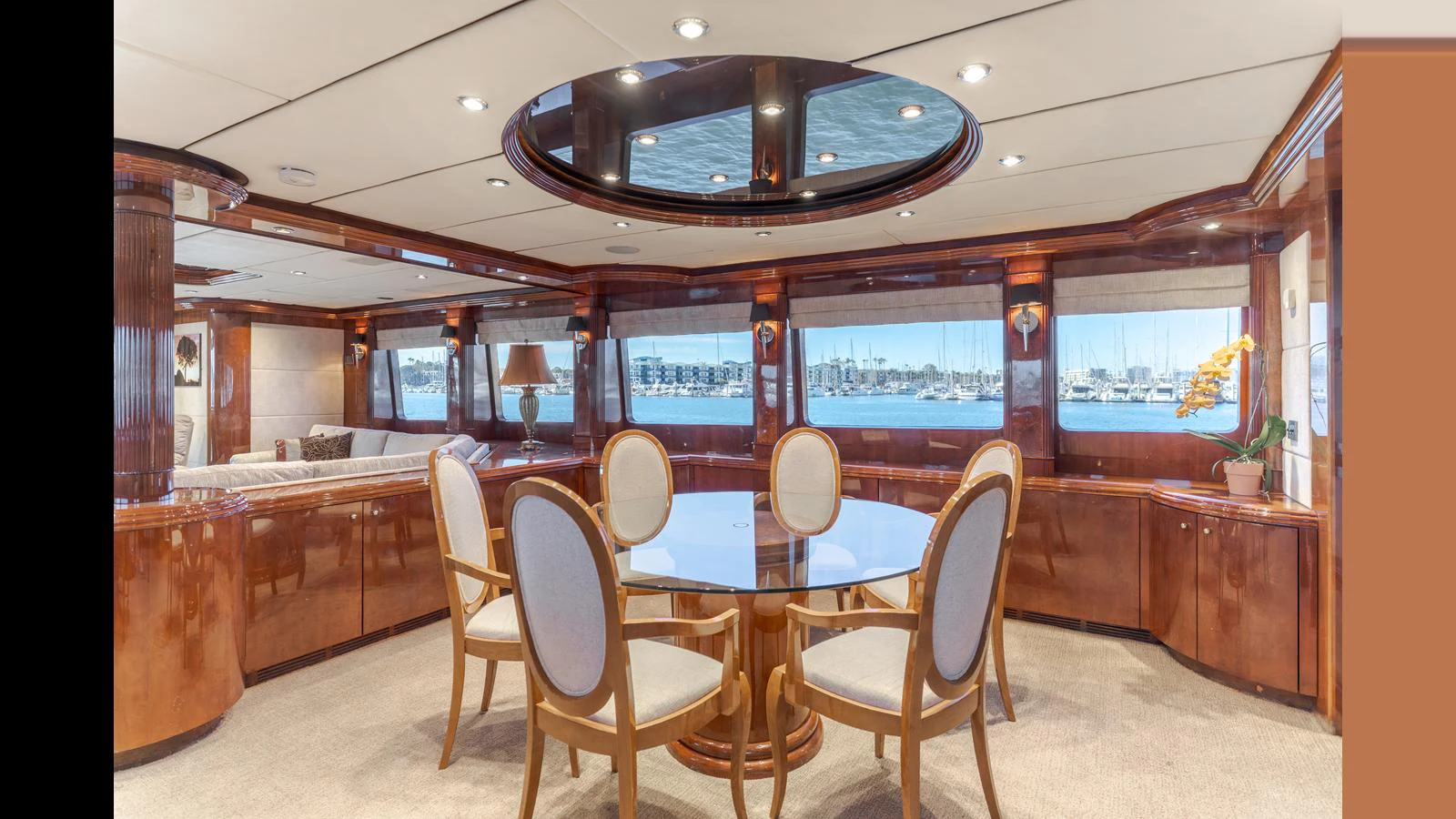 The yacht's dining area features a round glass table surrounded by elegant chairs, with large windows offering a view of the marina. aboard ACTIVE OCTO Yacht for Sale