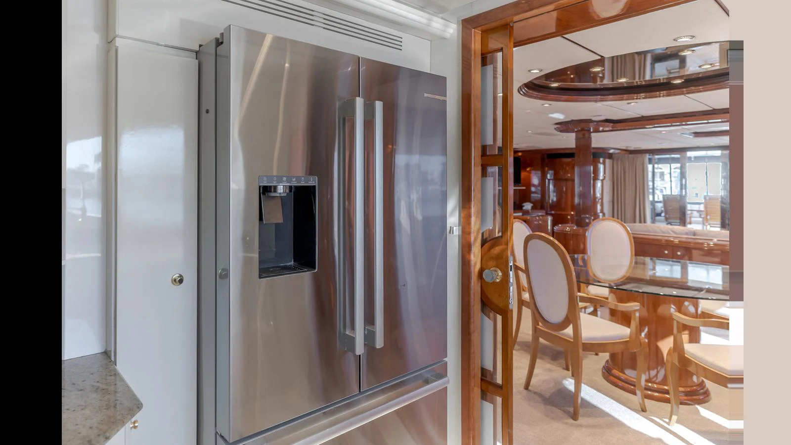 The galley features a modern stainless steel refrigerator adjacent to a stylish dining area. aboard ACTIVE OCTO Yacht for Sale