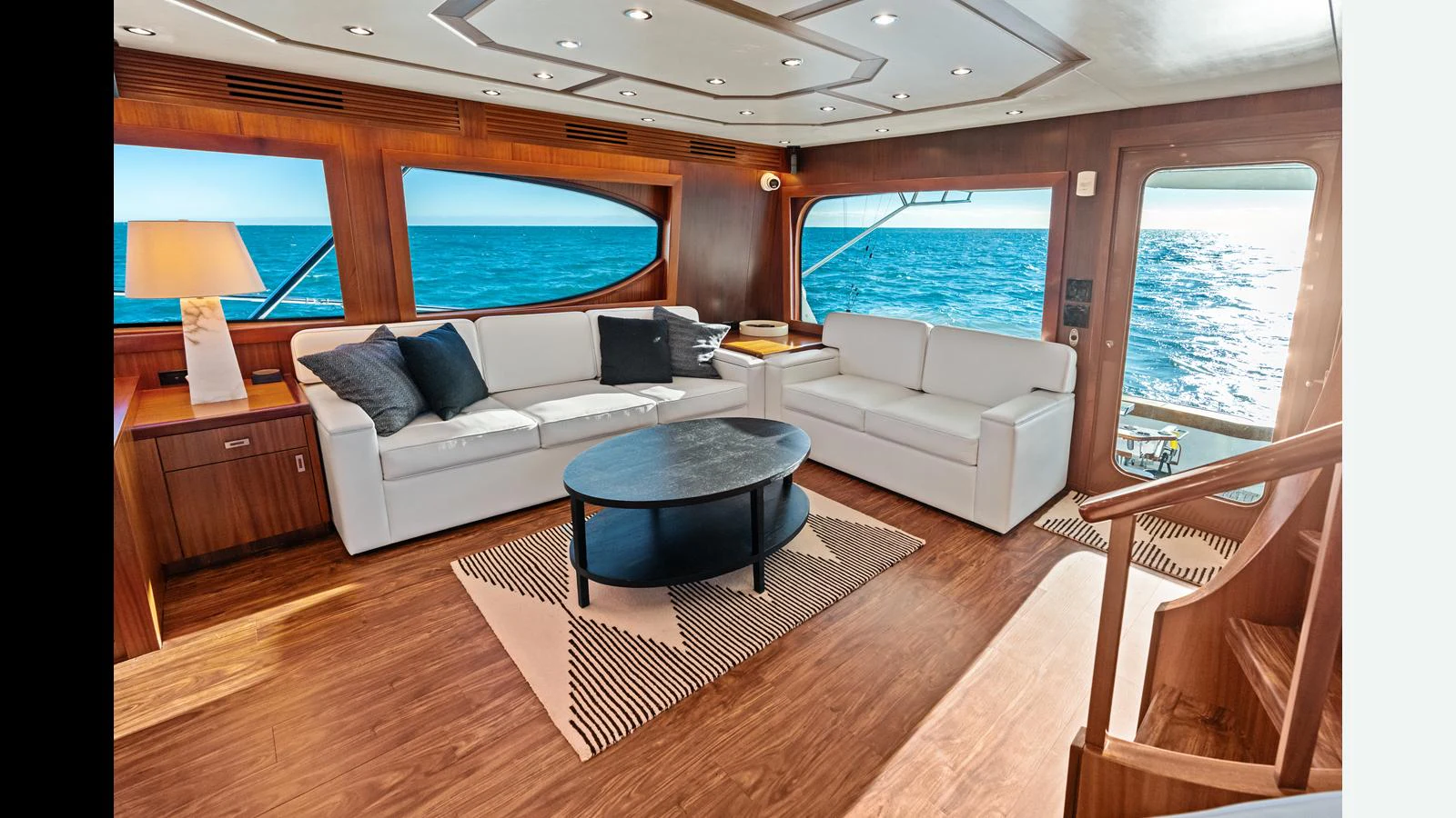 The salon features elegant seating with a stunning ocean view through large windows. aboard FIRTH'S CHASM Yacht for Sale
