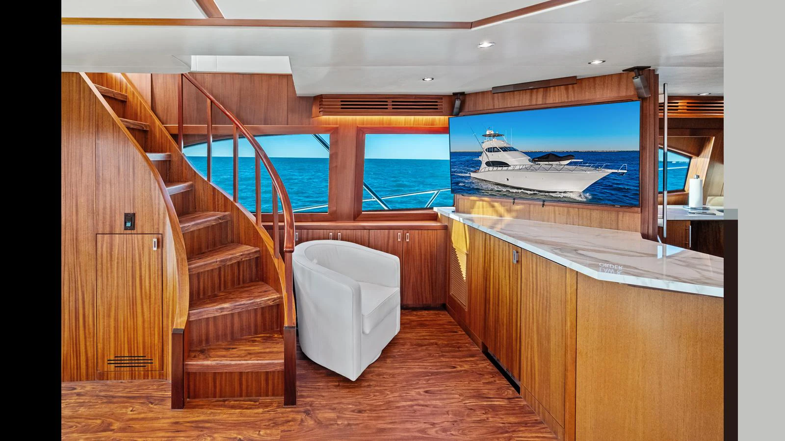 The salon features elegant wood finishes, a curved staircase, and a comfortable seating area with a view of the sea. aboard FIRTH'S CHASM Yacht for Sale