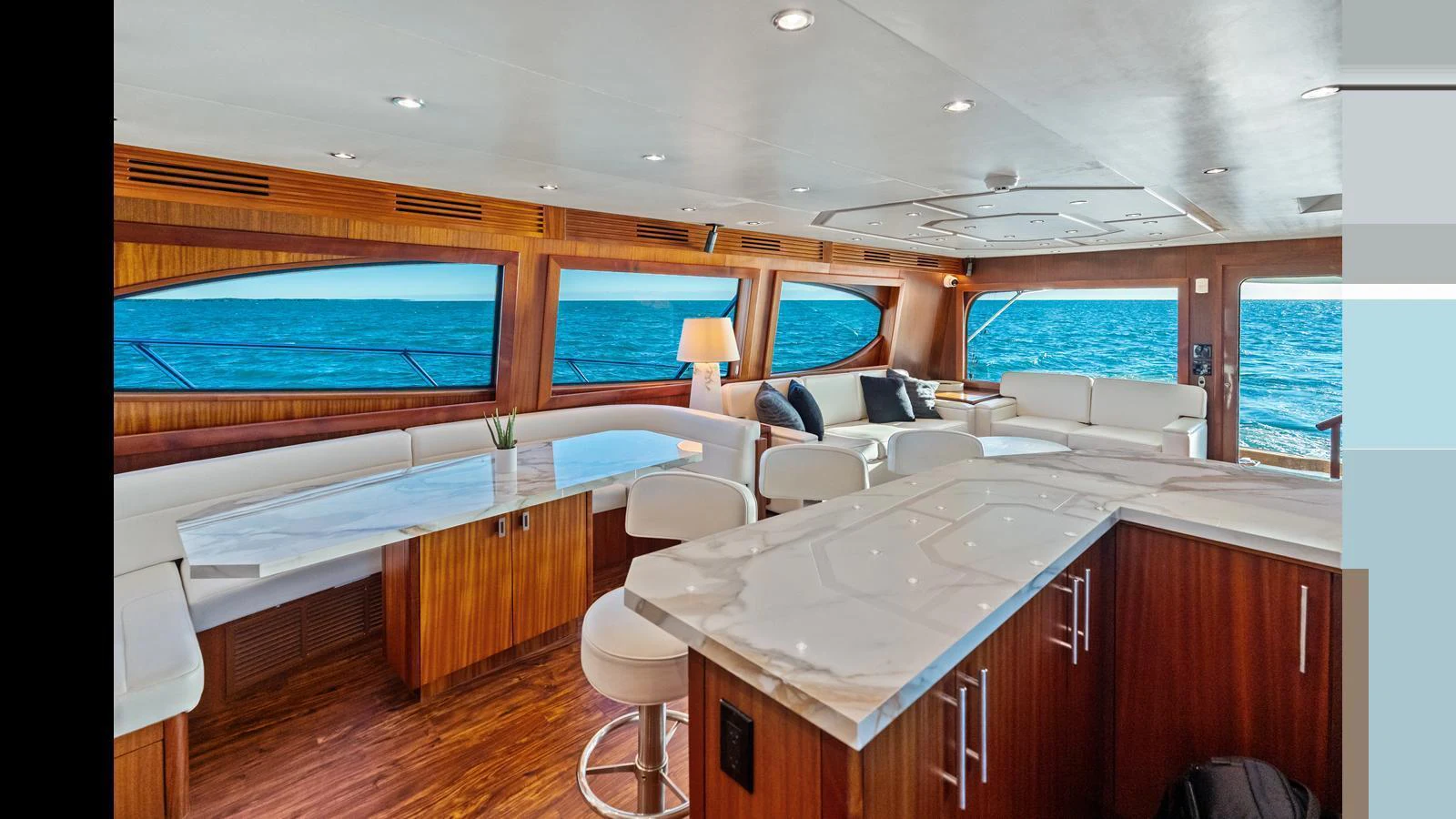 The salon features luxurious seating, a marble-topped bar, and expansive ocean views through large windows. aboard FIRTH'S CHASM Yacht for Sale