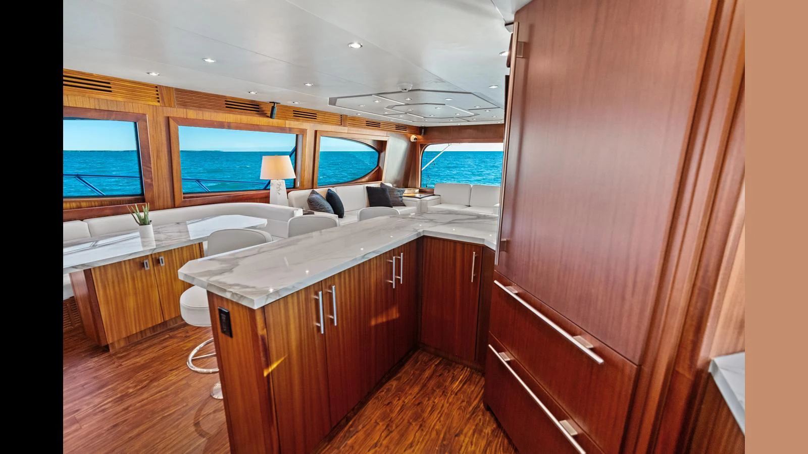 The yacht's galley features elegant wood cabinetry and modern appliances, with a view of the ocean through large windows. aboard FIRTH'S CHASM Yacht for Sale