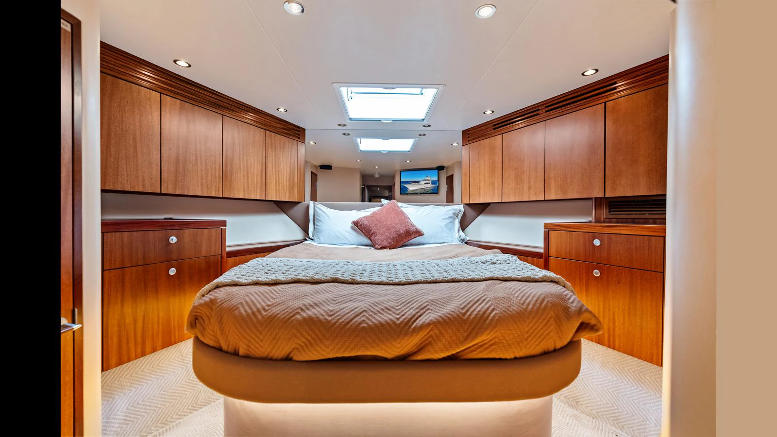 The master stateroom features a luxurious bed with warm wood cabinetry and ample lighting. aboard FIRTH'S CHASM Yacht for Sale