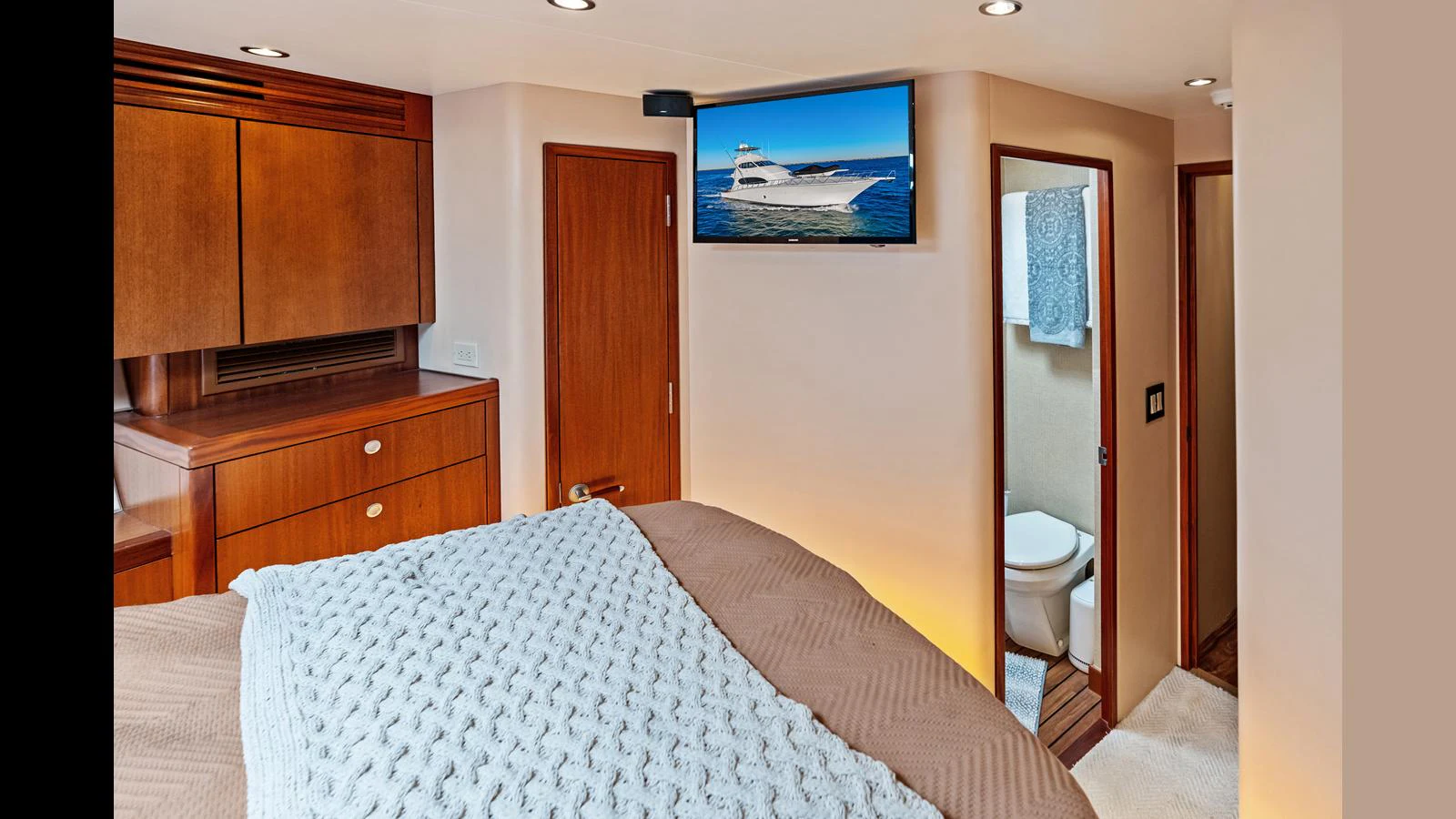 A cozy stateroom featuring a comfortable bed, wooden cabinetry, and an en-suite bathroom. aboard FIRTH'S CHASM Yacht for Sale