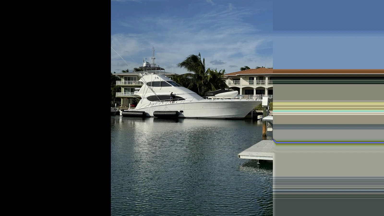 A sleek white yacht is docked in a serene marina with buildings in the background. aboard FIRTH'S CHASM Yacht for Sale