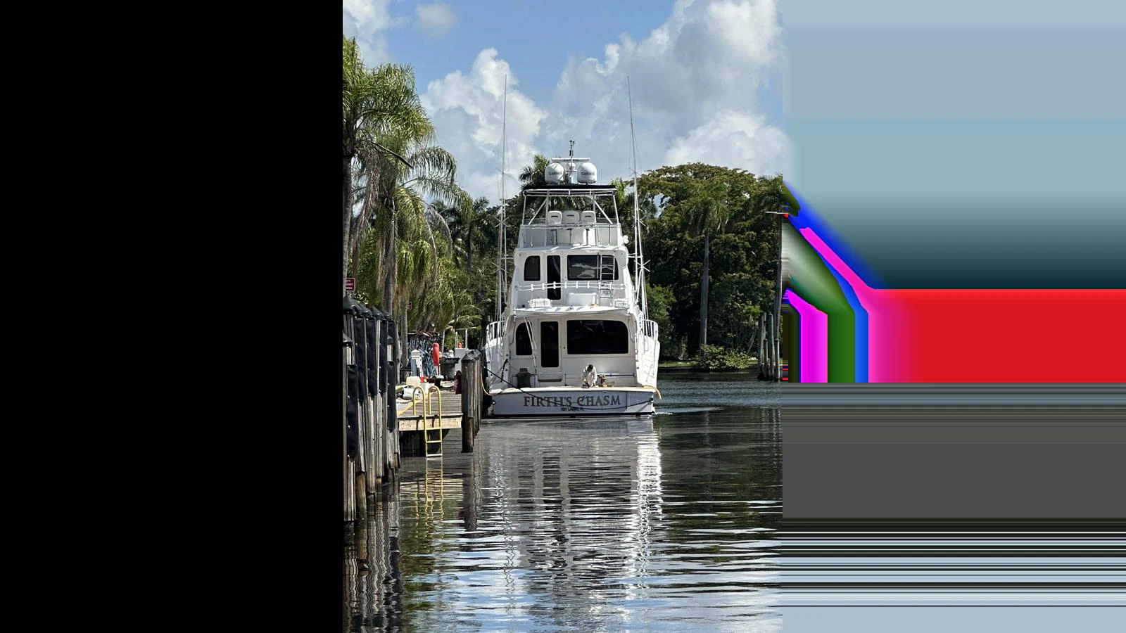 A yacht is docked in a serene marina surrounded by lush greenery. aboard FIRTH'S CHASM Yacht for Sale