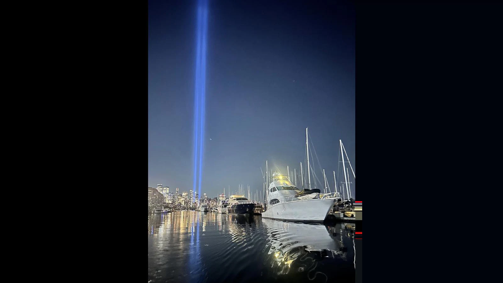 A sleek yacht is docked at a marina under a night sky illuminated by a striking beam of light. aboard FIRTH'S CHASM Yacht for Sale