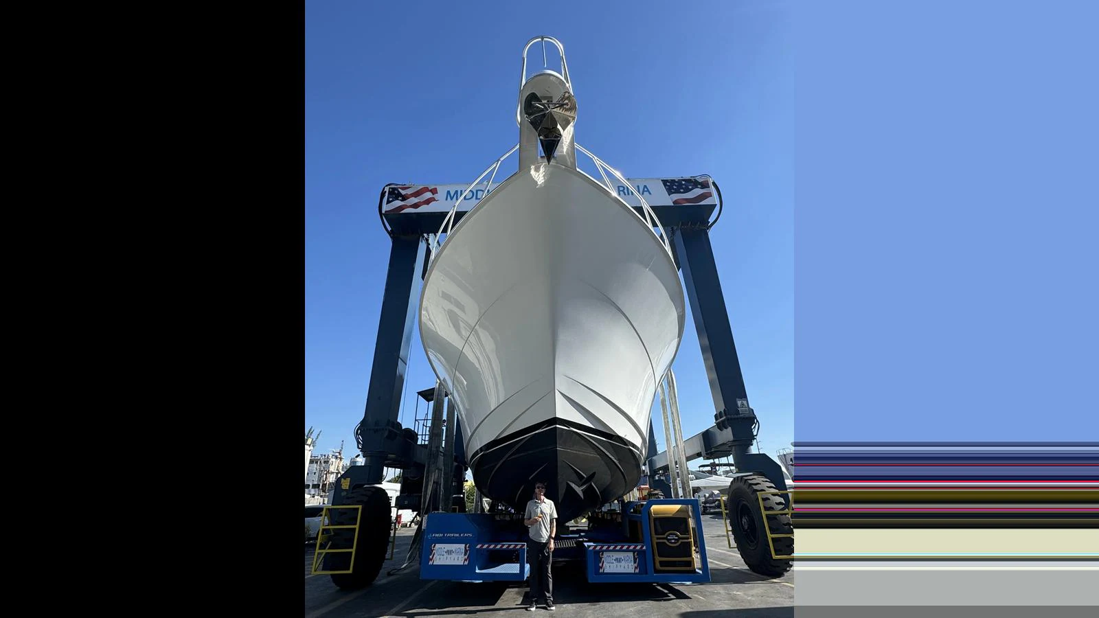 The yacht is being lifted out of the water by a large boat lift, showcasing its sleek hull design. aboard FIRTH'S CHASM Yacht for Sale