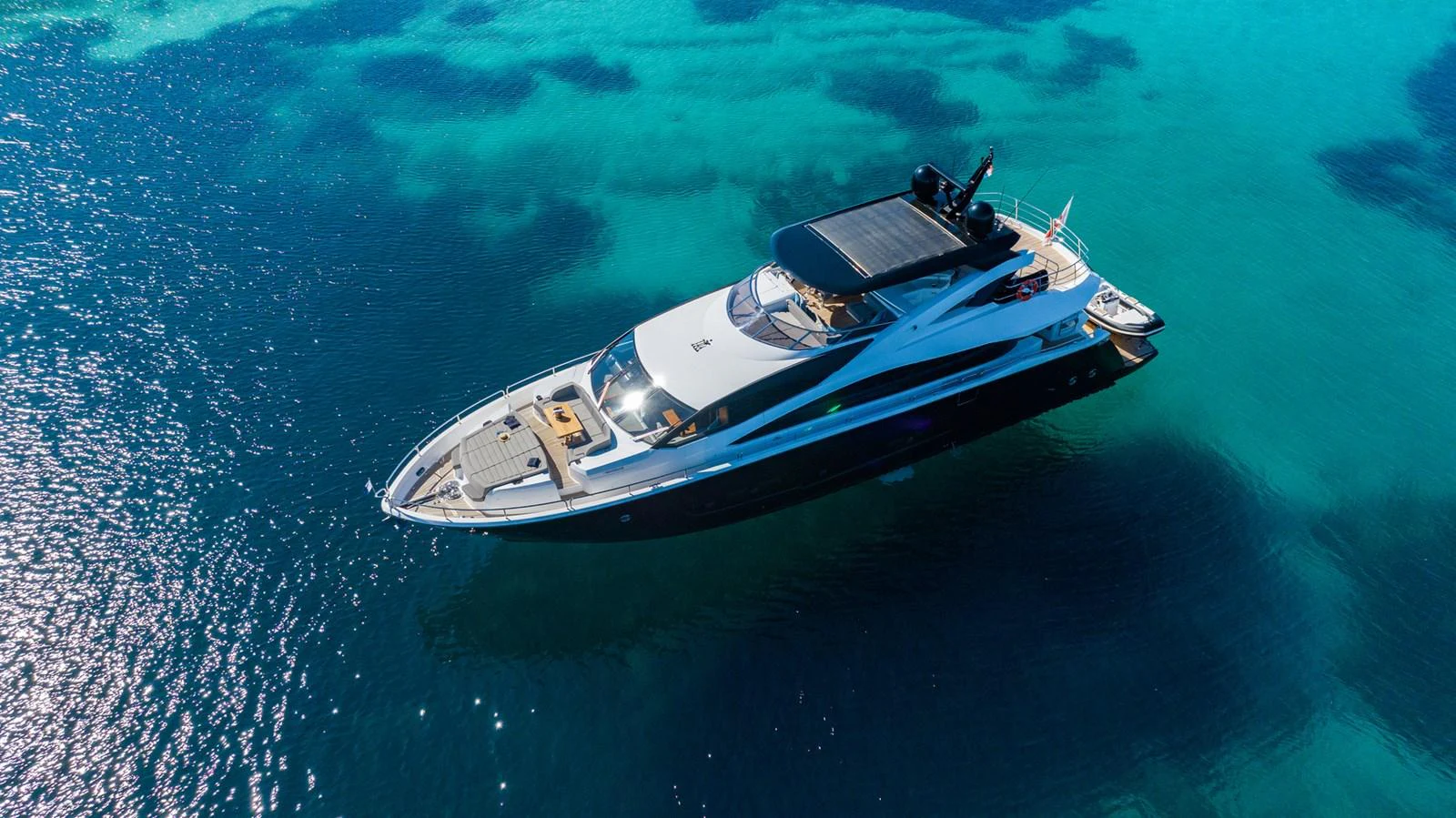 A sleek yacht glides over crystal-clear waters, showcasing its elegant design and luxurious amenities. aboard BLACK MAMBA Yacht for Sale