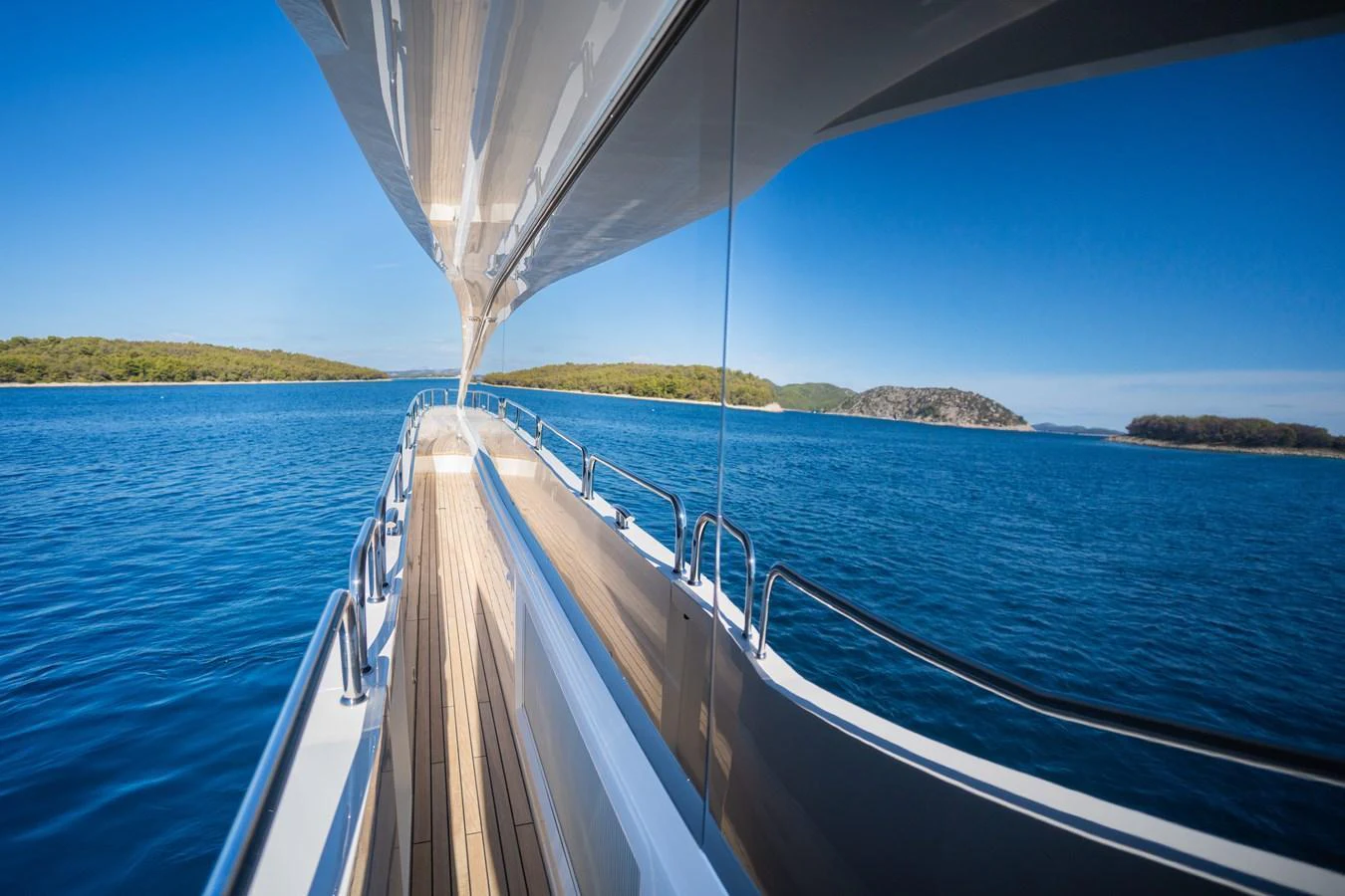 A sleek yacht cruises through pristine blue waters, reflecting the serene landscape on its polished surfaces. aboard BLACK MAMBA Yacht for Sale