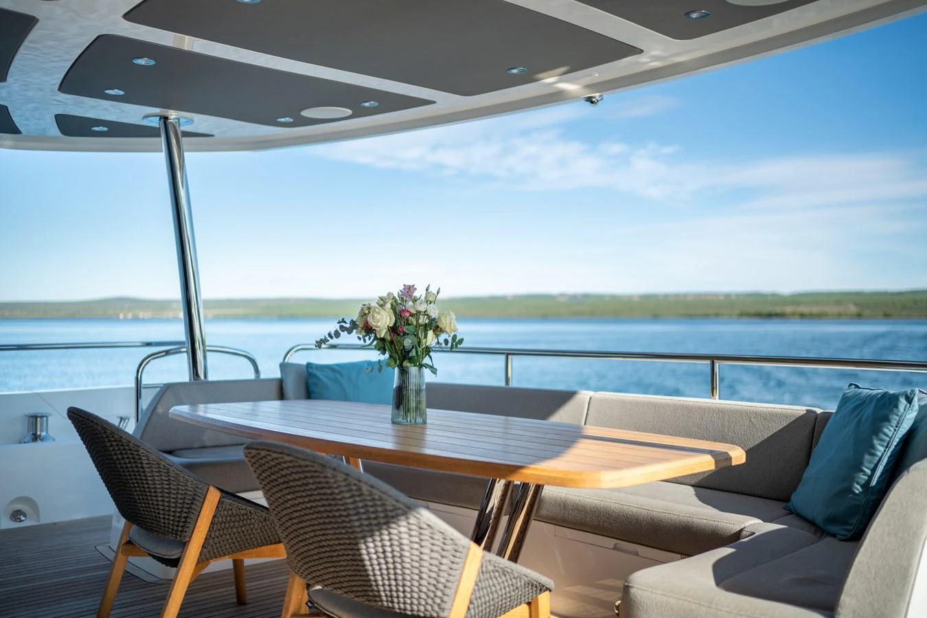 The aft deck features a stylish dining area with a wooden table and comfortable seating, offering stunning views of the water. aboard BLACK MAMBA Yacht for Sale