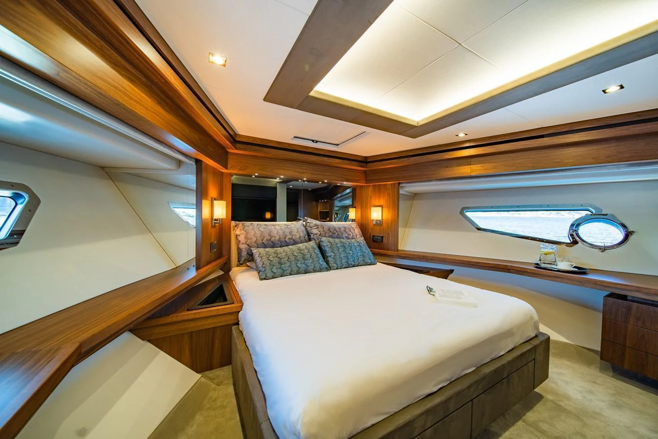 The stateroom features a luxurious bed with elegant wood paneling and ample natural light from the windows. aboard BLACK MAMBA Yacht for Sale