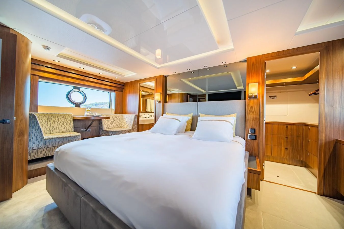 The master stateroom features a luxurious bed with elegant wood paneling and ample natural light. aboard BLACK MAMBA Yacht for Sale