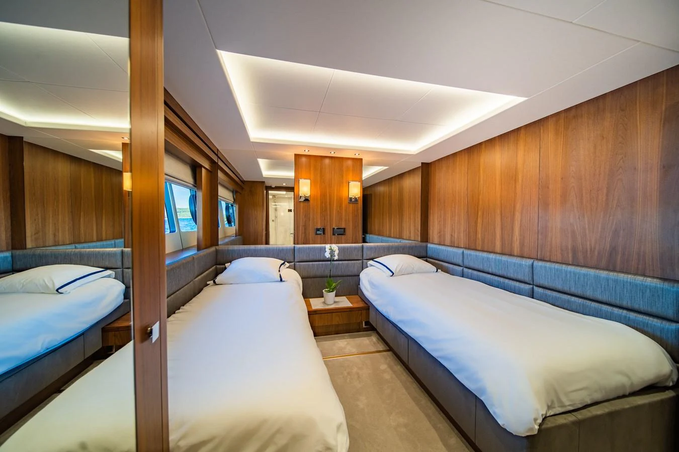 The twin stateroom features two comfortable beds with elegant wood paneling and soft lighting. aboard BLACK MAMBA Yacht for Sale