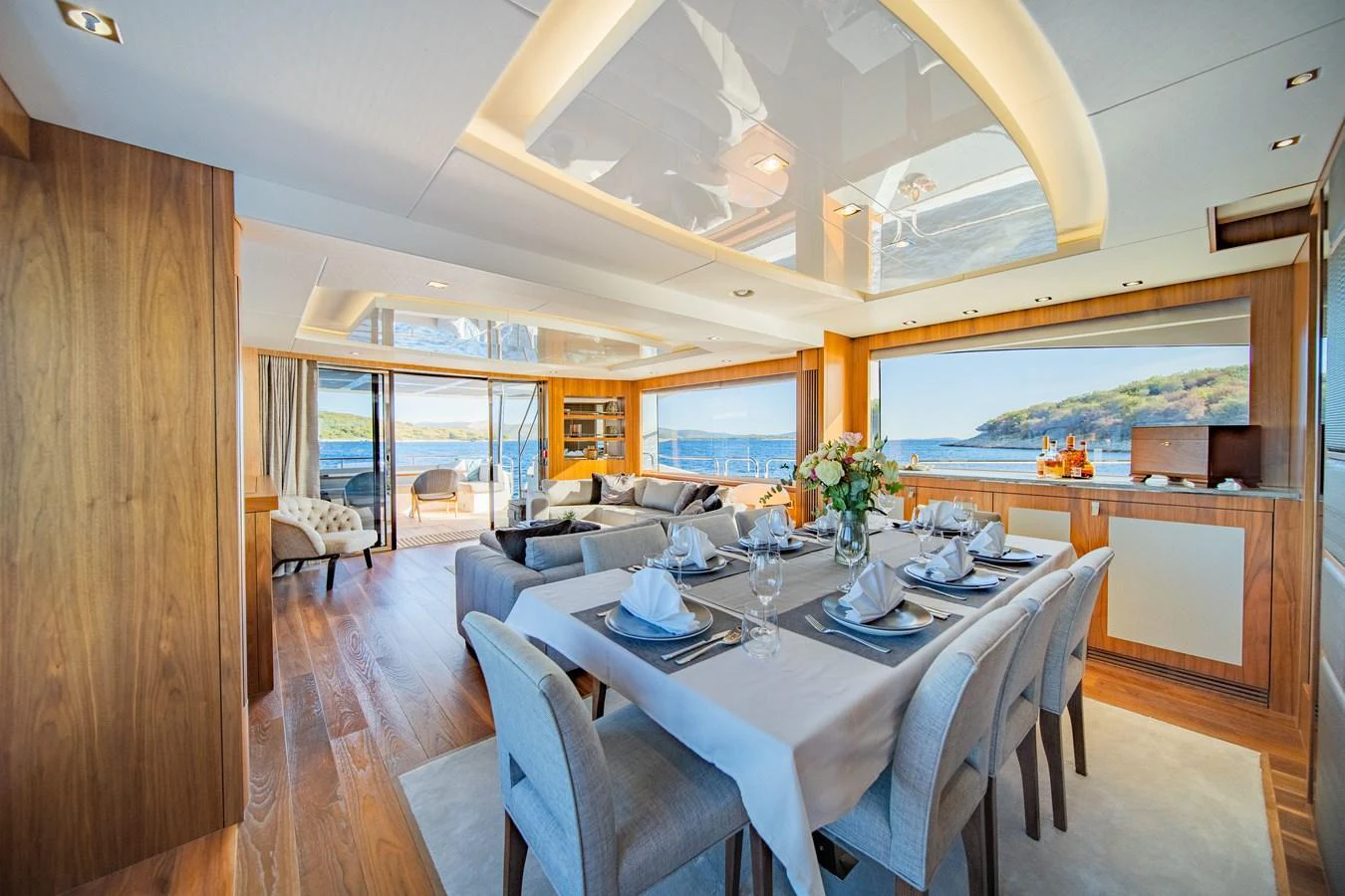 The yacht's salon features a spacious dining area with elegant table settings and a comfortable lounge with panoramic views. aboard BLACK MAMBA Yacht for Sale