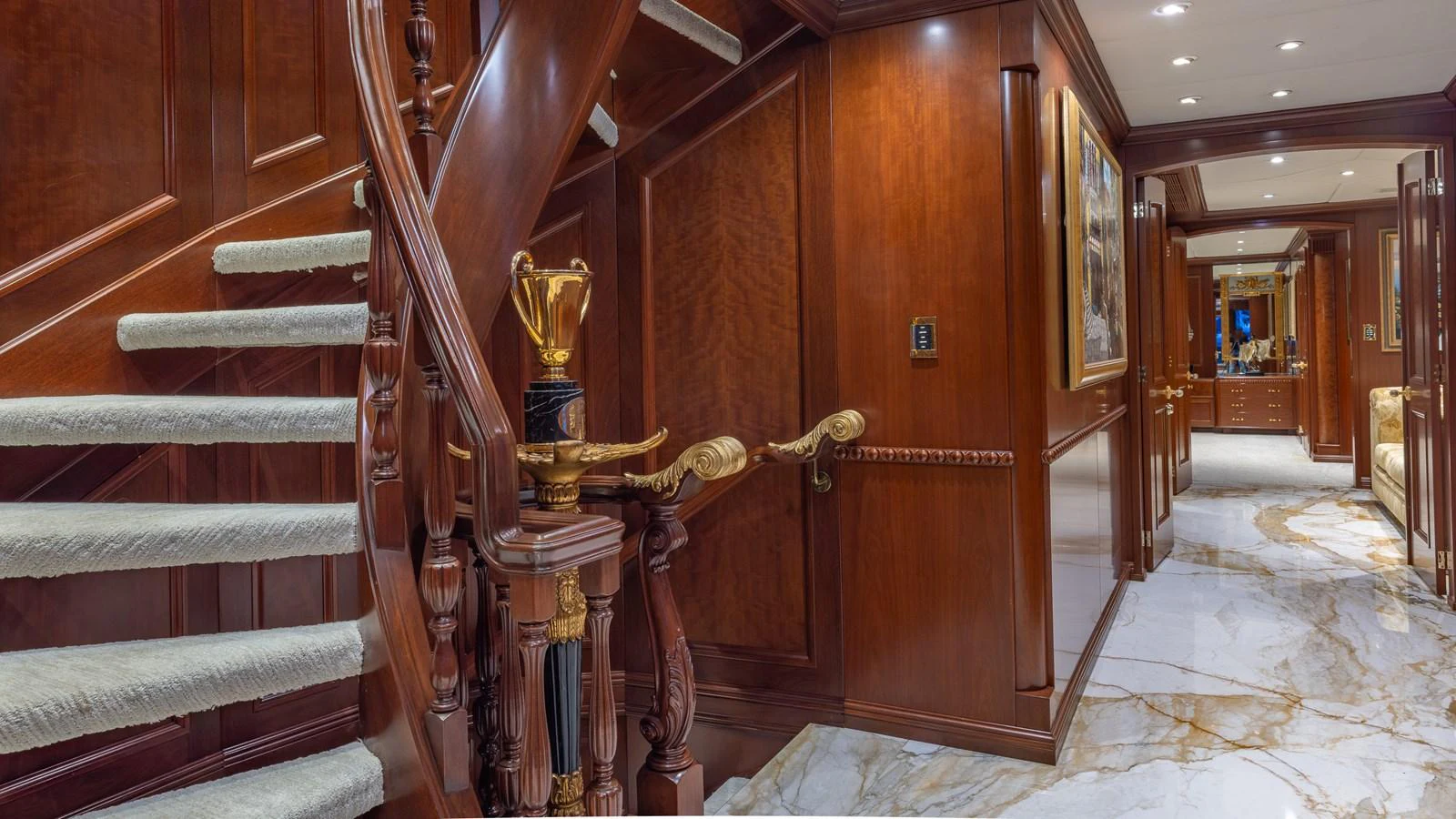 The yacht's interior features a luxurious staircase with rich wood paneling and marble flooring. aboard RELENTLESS Yacht for Sale