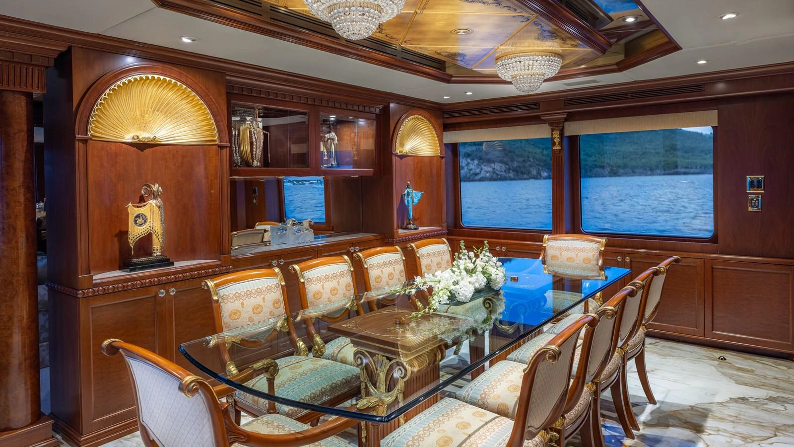 The yacht's dining room features an elegant glass table surrounded by luxurious chairs, with large windows offering stunning sea views. aboard RELENTLESS Yacht for Sale