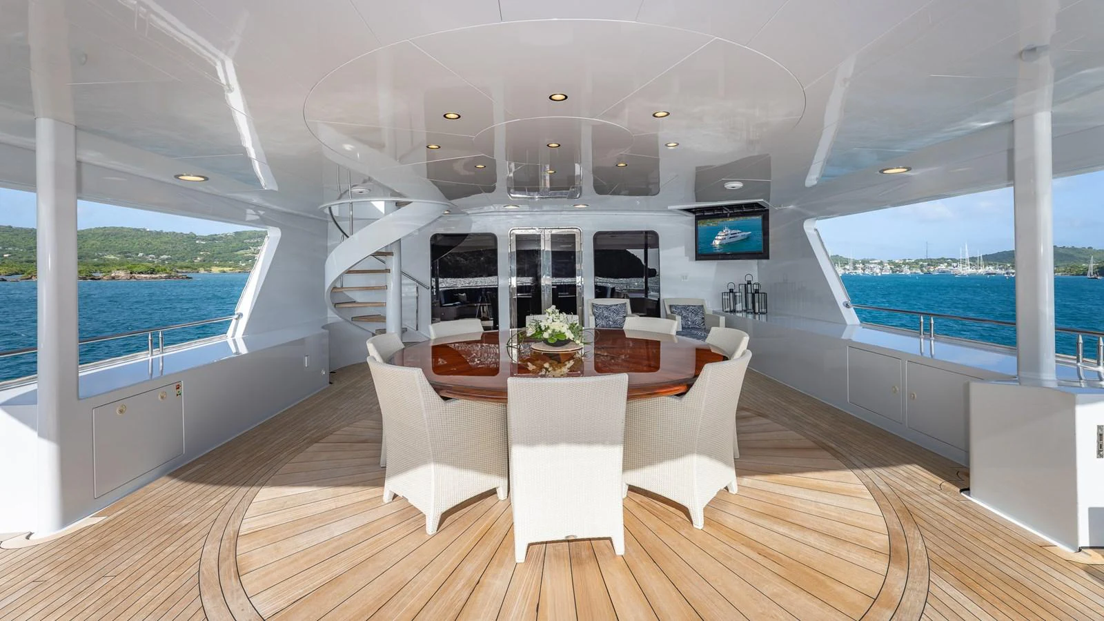 The aft deck features a spacious dining area with a large round table and comfortable chairs, perfect for alfresco meals with a view. aboard RELENTLESS Yacht for Sale