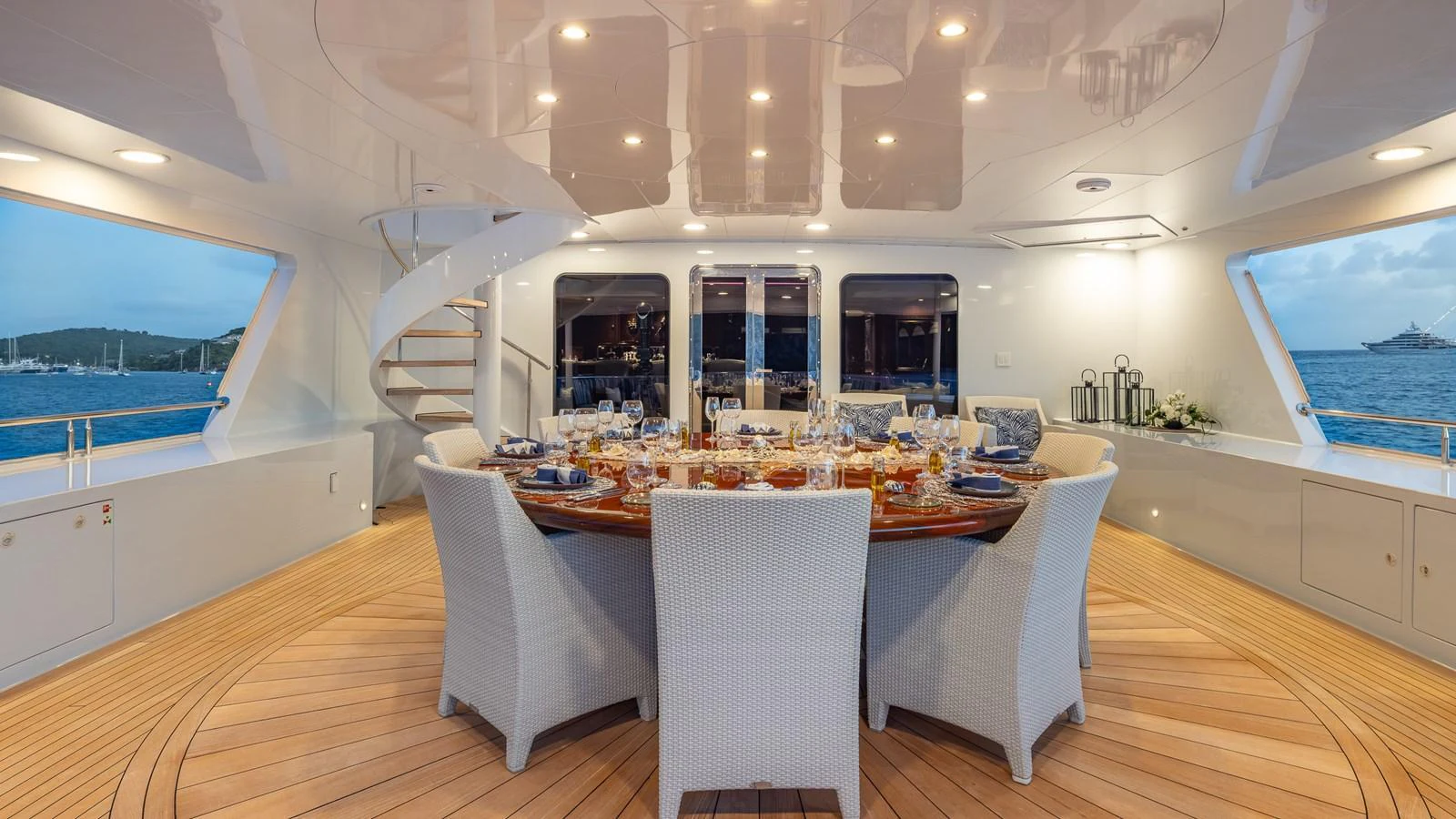 The aft deck features an elegant dining area with a large round table and comfortable wicker chairs, perfect for alfresco dining. aboard RELENTLESS Yacht for Sale