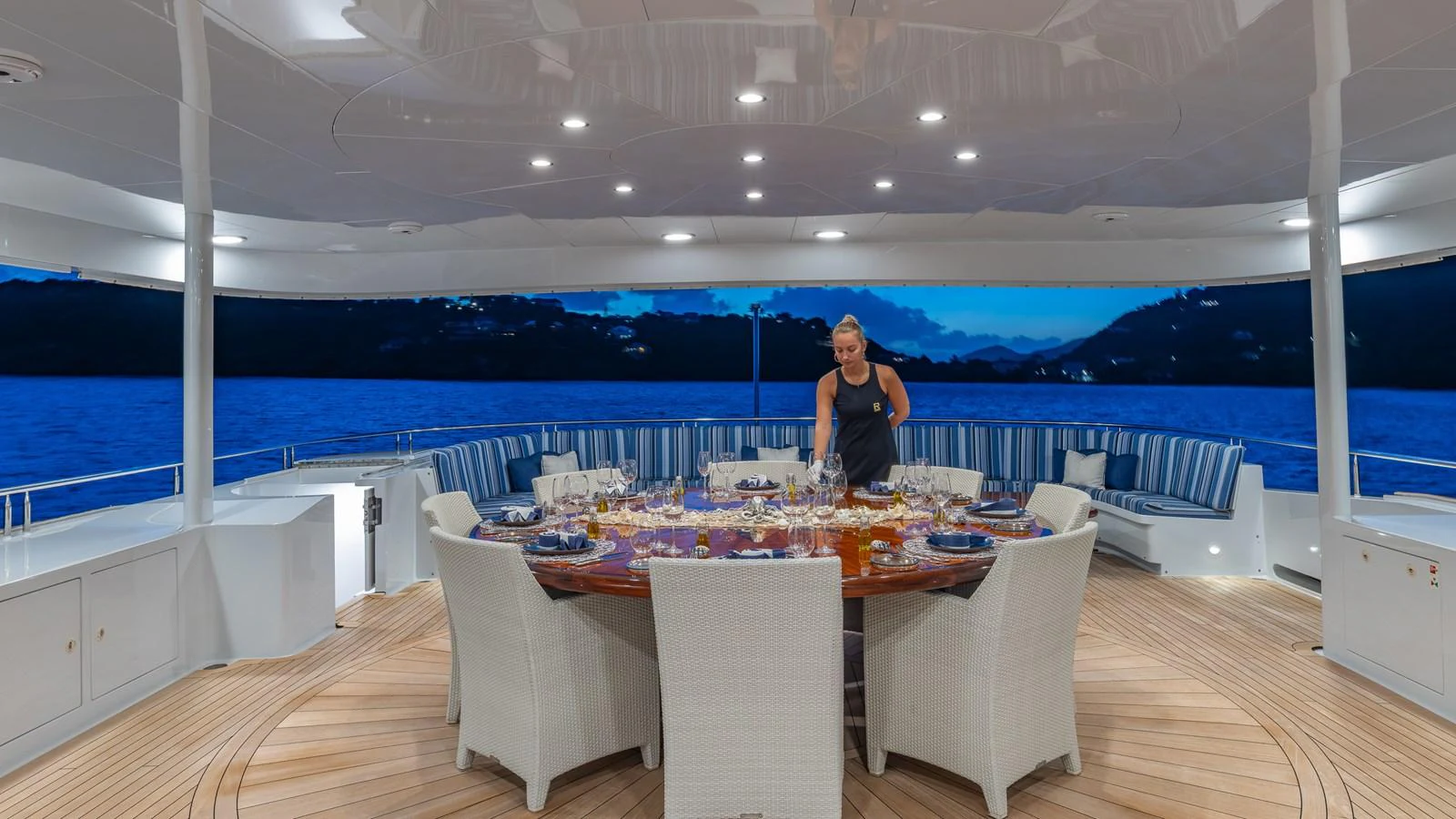The aft deck features an elegant dining area with a large round table and comfortable seating, perfect for enjoying meals with a view. aboard RELENTLESS Yacht for Sale