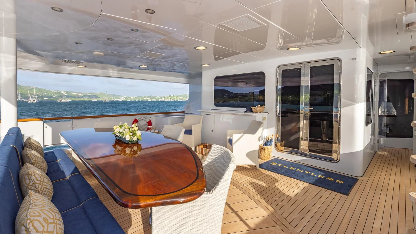 The aft deck features a spacious seating area with a polished wooden table, offering stunning views of the surrounding waters. aboard RELENTLESS Yacht for Sale