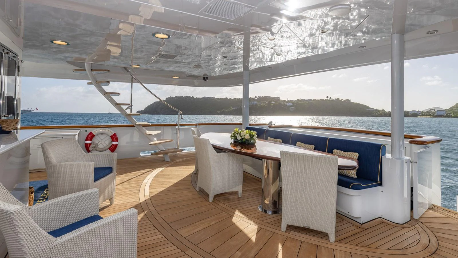 The aft deck features a spacious seating area with a dining table, offering stunning views of the surrounding waters. aboard RELENTLESS Yacht for Sale