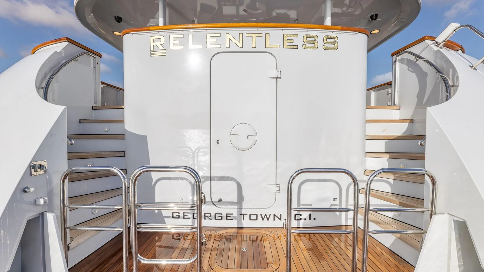 The aft deck features elegant stairs and polished railings, showcasing the yacht's name prominently. aboard RELENTLESS Yacht for Sale