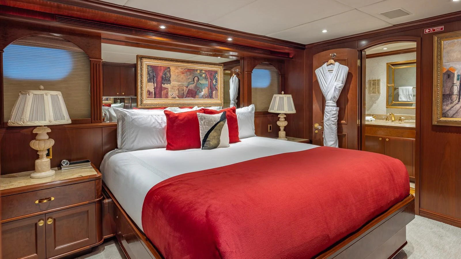 The master stateroom features a luxurious bed with rich red accents and elegant wooden furnishings. aboard RELENTLESS Yacht for Sale