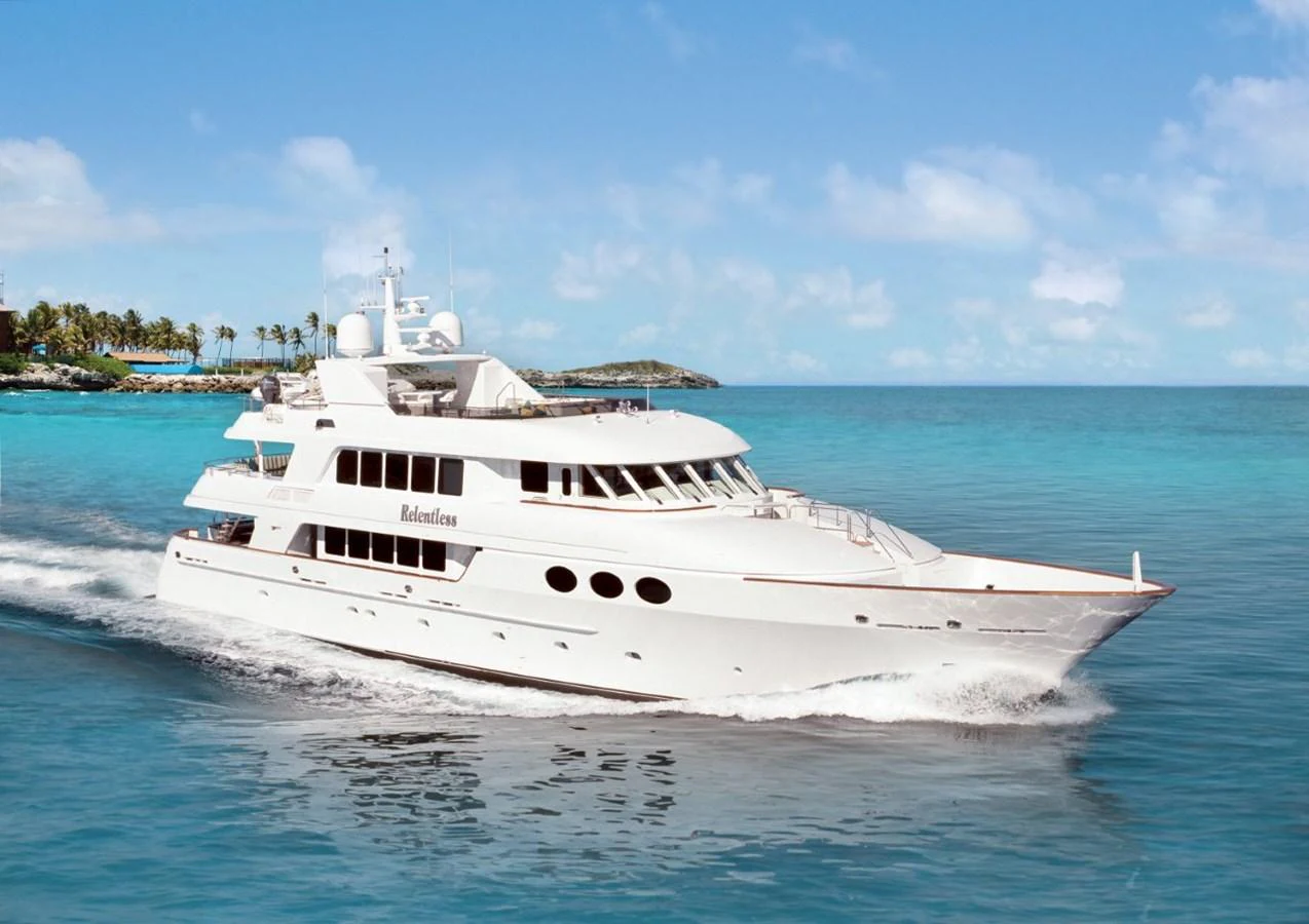 A luxurious yacht cruises through clear blue waters under a bright sky. aboard RELENTLESS Yacht for Sale