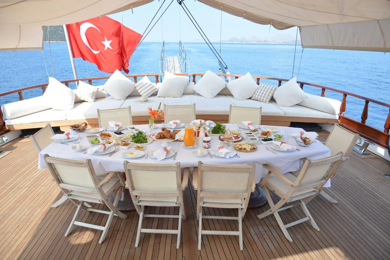 The aft deck features a beautifully set dining table under a shaded canopy, perfect for alfresco meals with a view of the sea. aboard PAPA JOE Yacht for Sale
