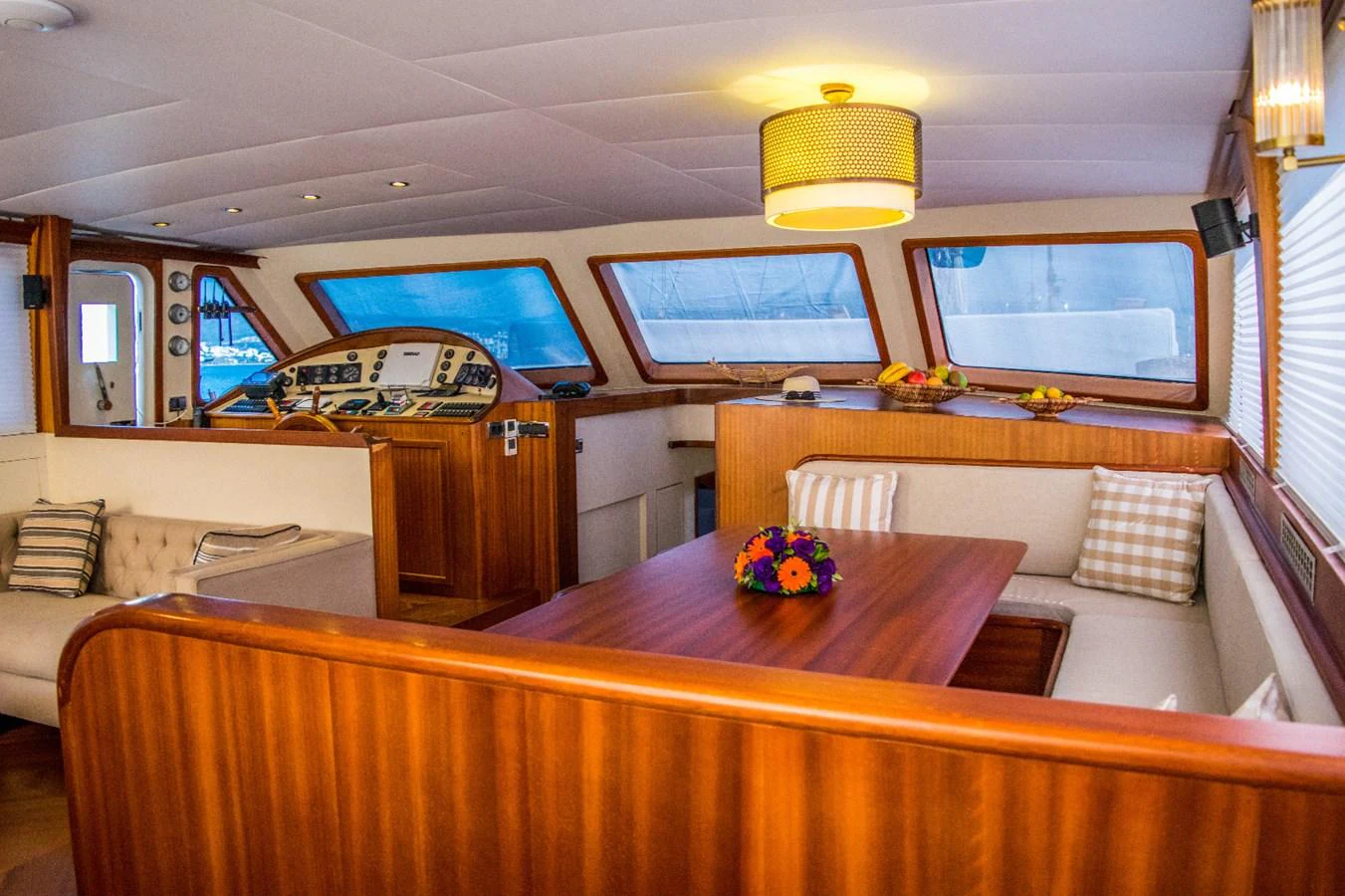 The yacht's saloon features a cozy seating area with a wooden table and large windows offering ample natural light. aboard PAPA JOE Yacht for Sale
