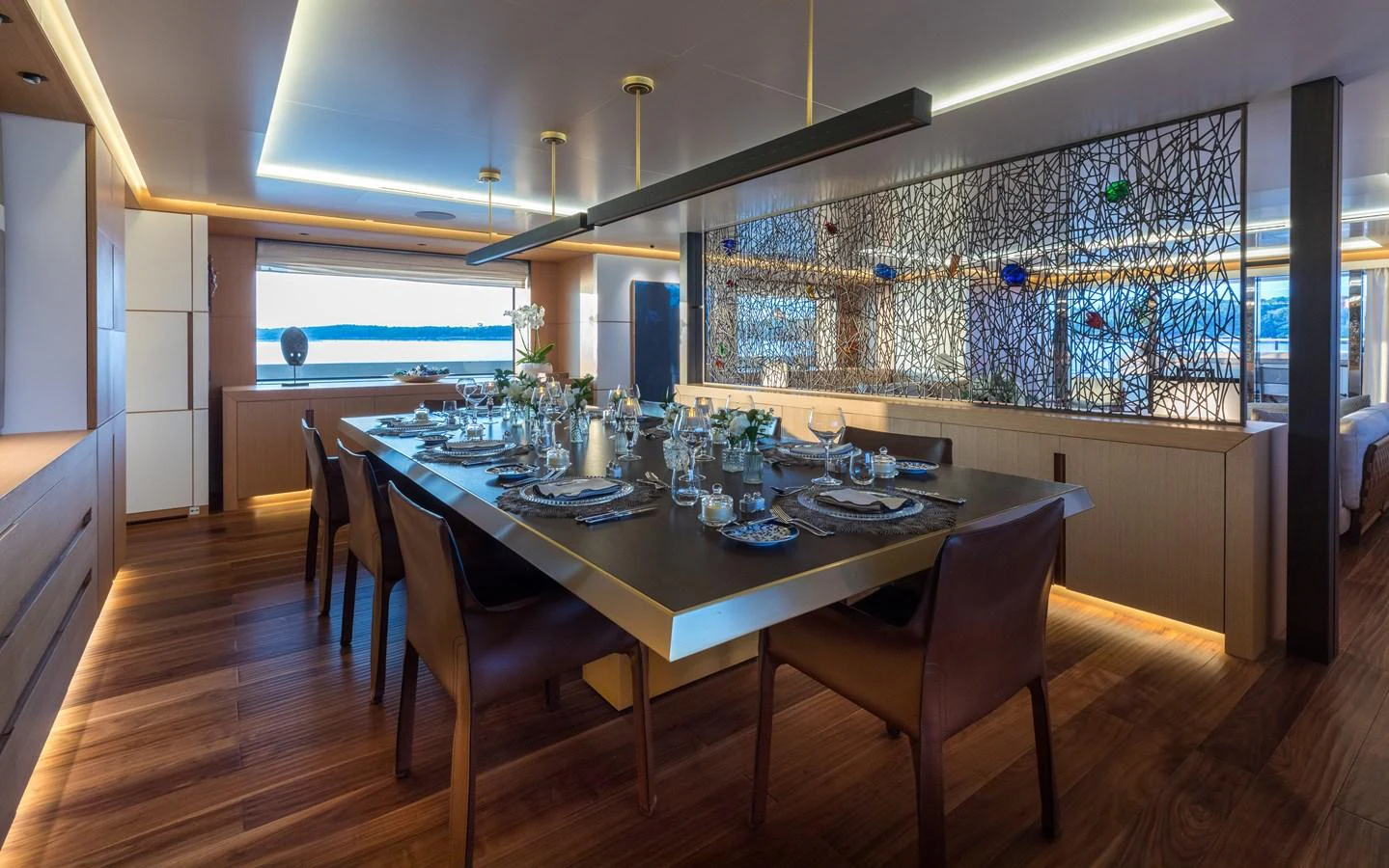 The yacht's dining area features a sophisticated table setting with elegant decor and ambient lighting. aboard ALCHEMIST Yacht for Sale