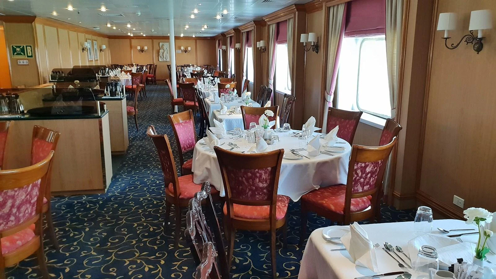 The yacht's elegant dining area is set with round tables and plush seating, ready for a fine dining experience. aboard MINERVA Yacht for Sale