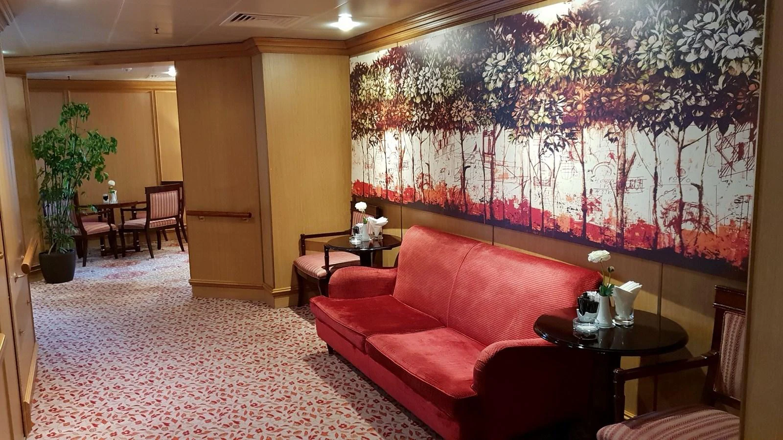 A cozy interior seating area with a red sofa and a large wall painting, creating a warm and inviting atmosphere. aboard MINERVA Yacht for Sale