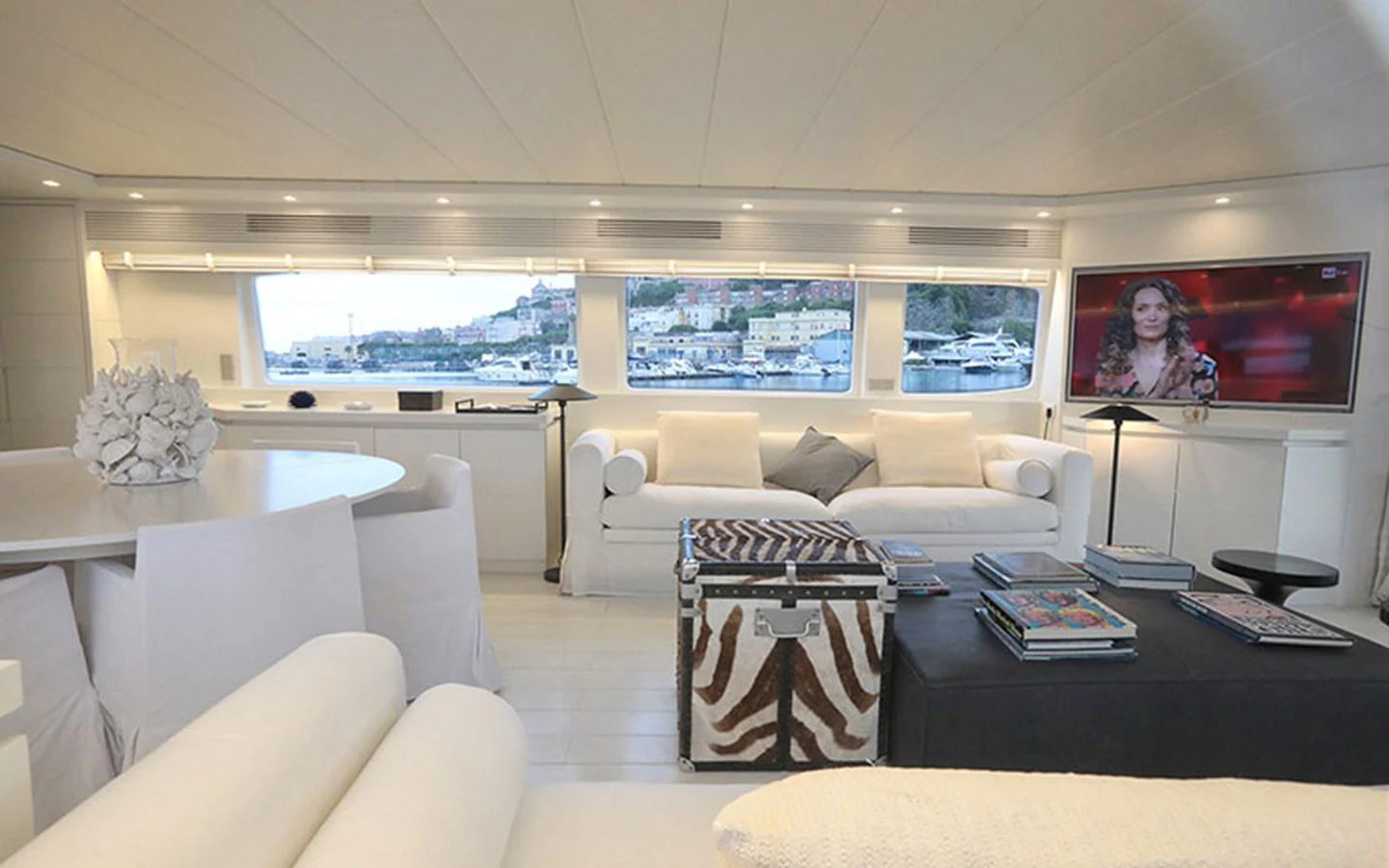 The salon features plush seating, a large television, and panoramic windows offering stunning views. aboard NIKCA Yacht for Sale