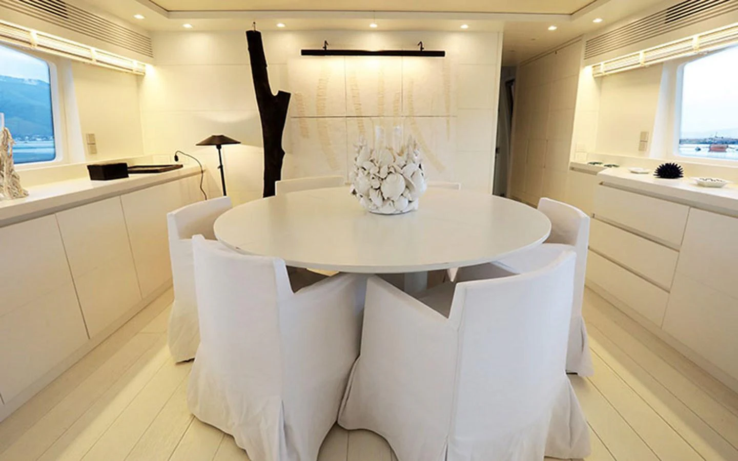 The yacht's dining area features a round table with elegant white chairs and modern decor. aboard NIKCA Yacht for Sale