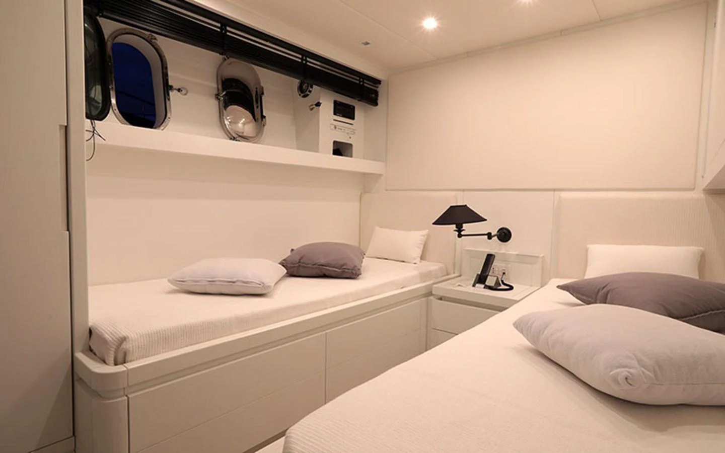 The guest cabin features twin beds with a minimalist design and soft lighting. aboard NIKCA Yacht for Sale