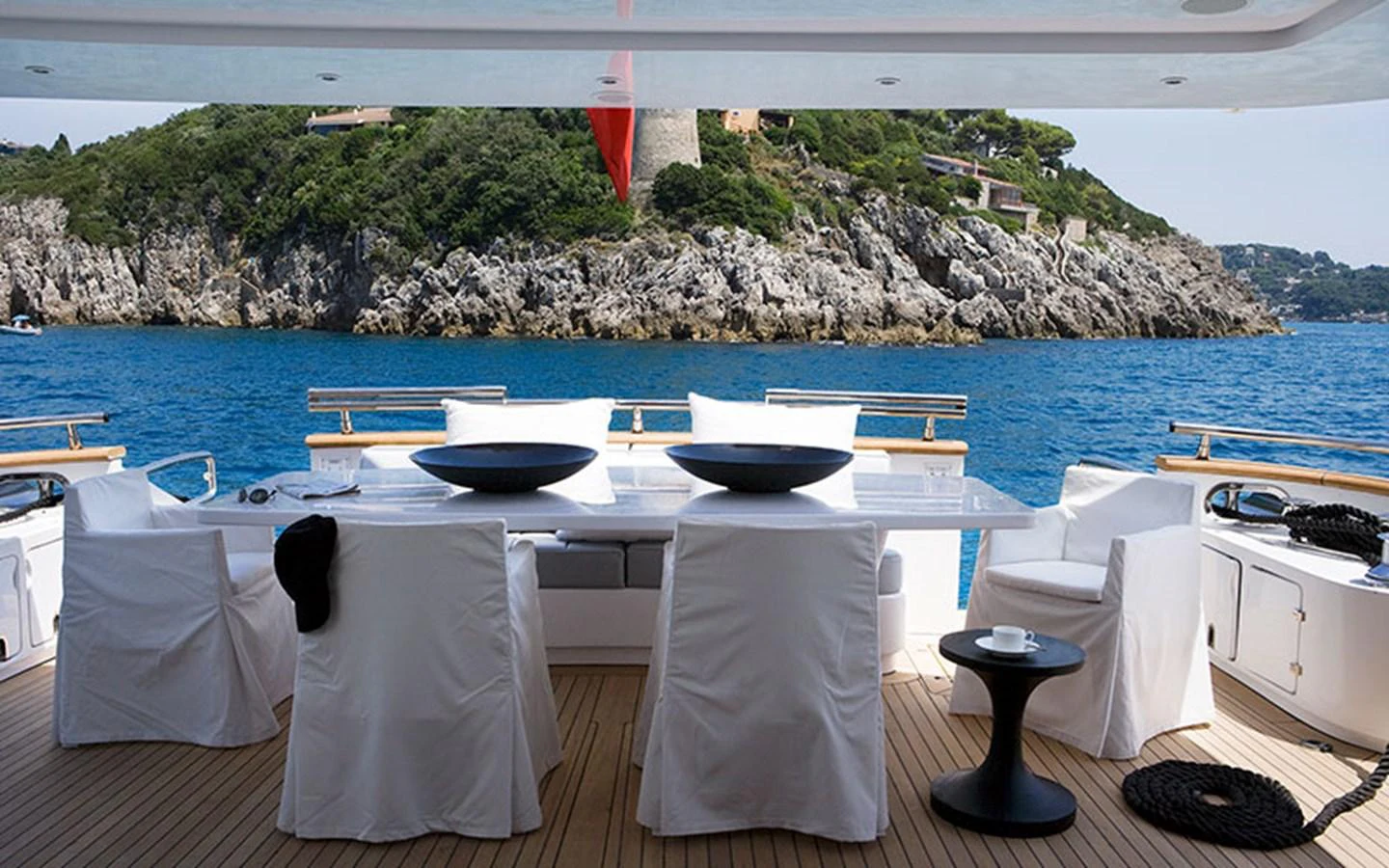 The aft deck features a stylish dining area with a stunning view of the surrounding landscape. aboard NIKCA Yacht for Sale