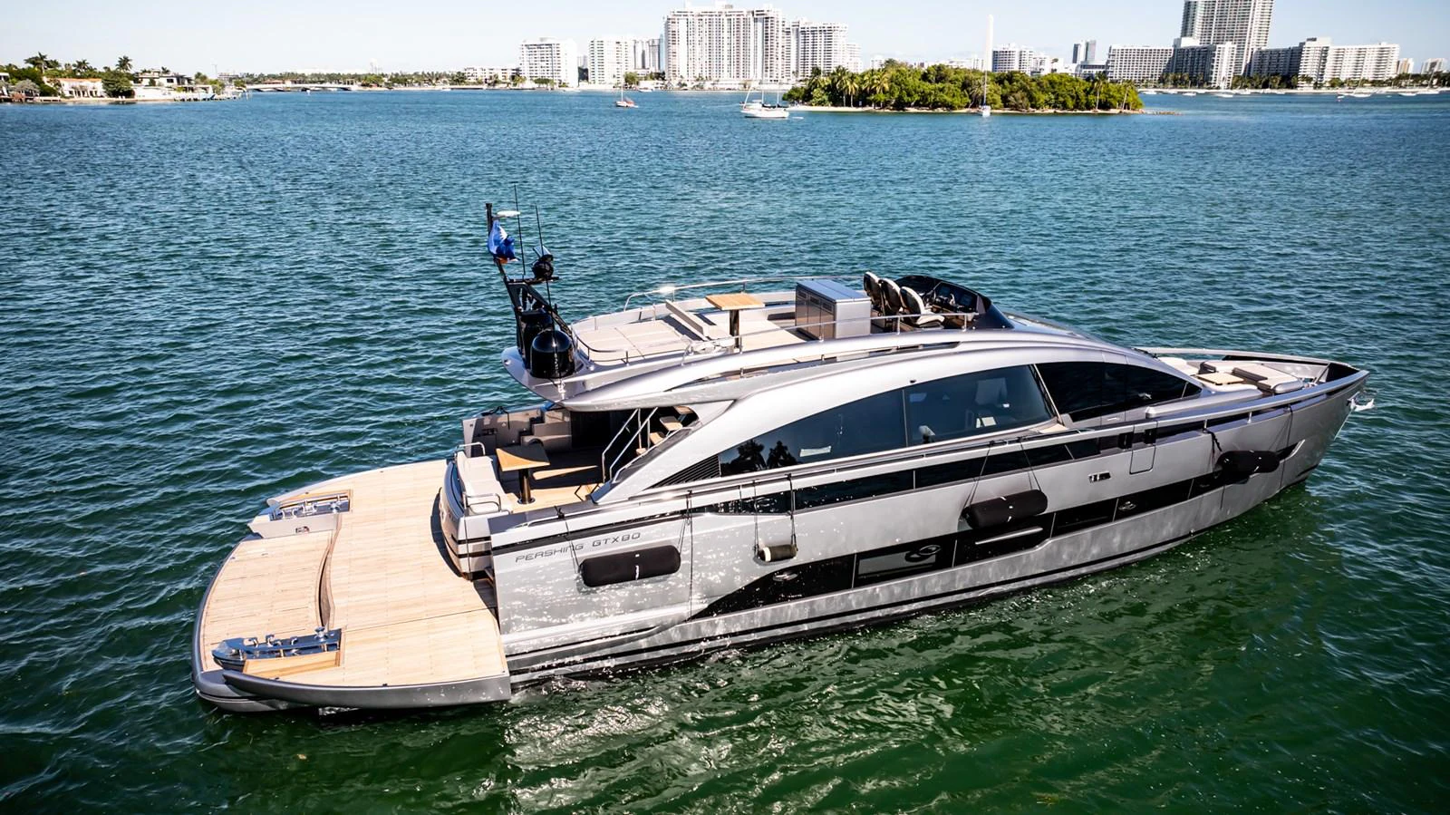 A sleek and modern yacht cruising on calm waters with a cityscape in the background. aboard CIAO Yacht for Sale