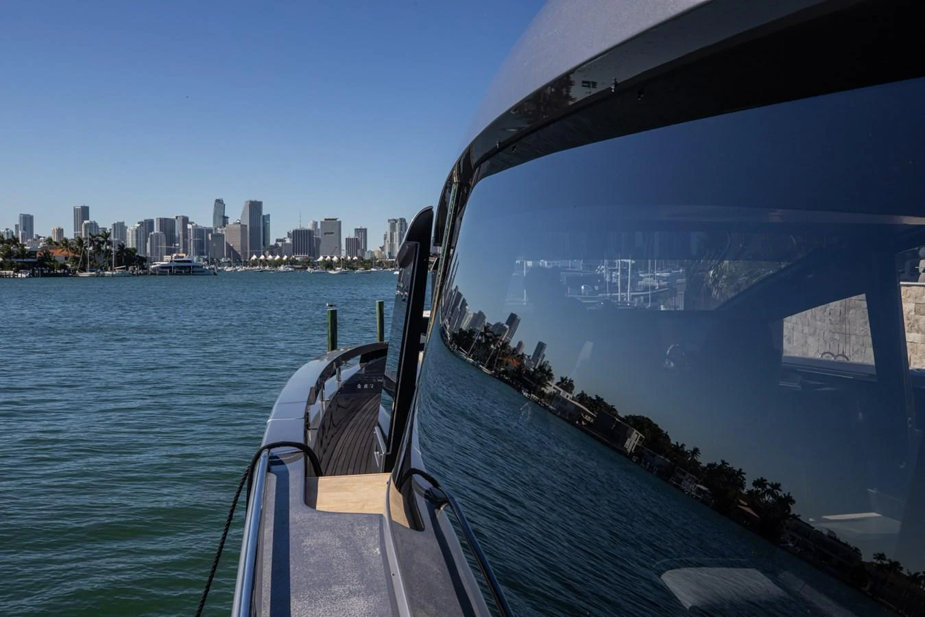 The yacht is docked with a city skyline in the background, reflecting on its sleek windows. aboard CIAO Yacht for Sale