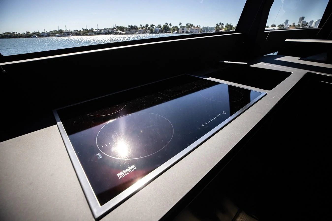The sleek galley features a modern induction cooktop with a scenic view of the water. aboard CIAO Yacht for Sale