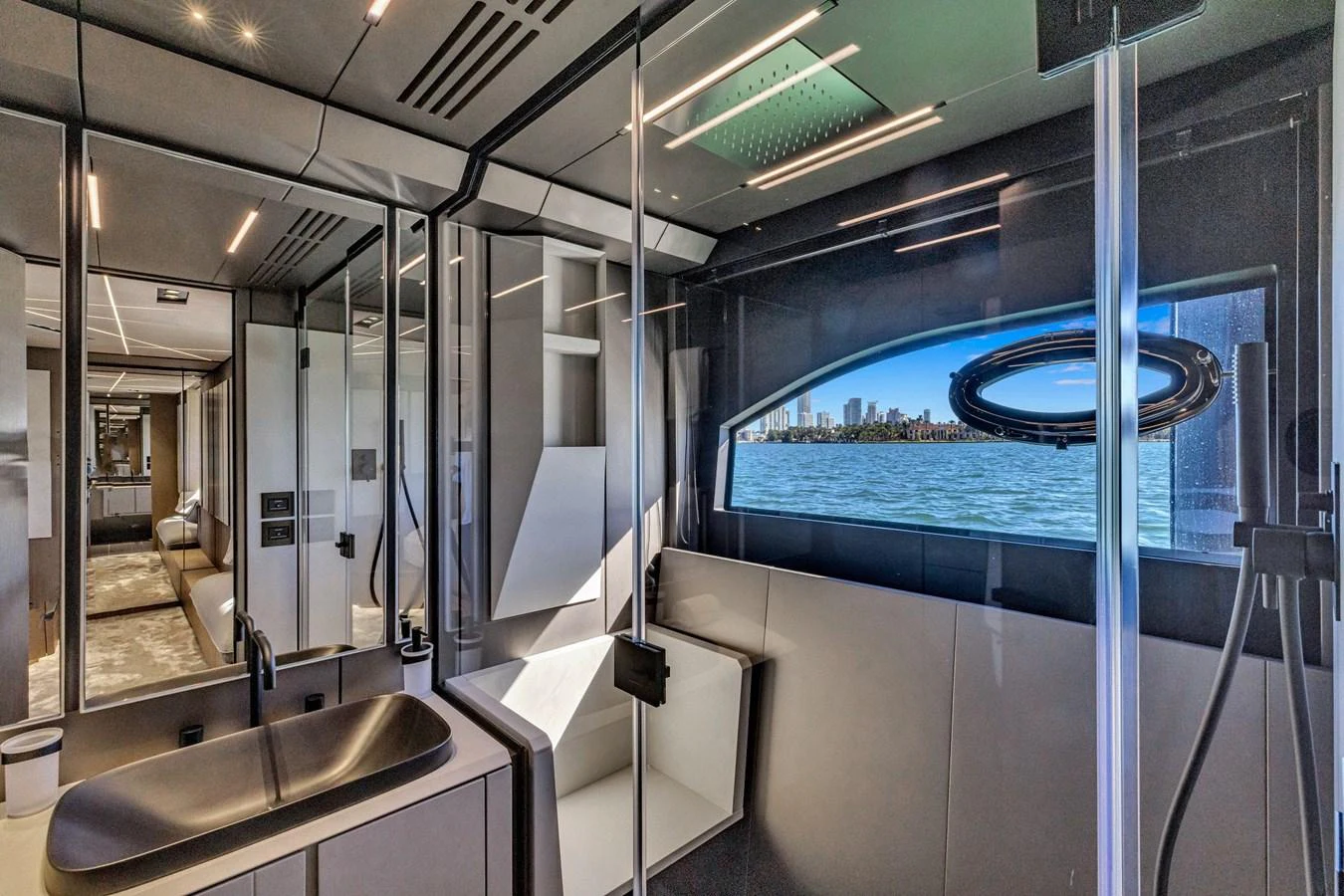 A sleek and modern bathroom with a large window offering a stunning view of the water and city skyline. aboard CIAO Yacht for Sale