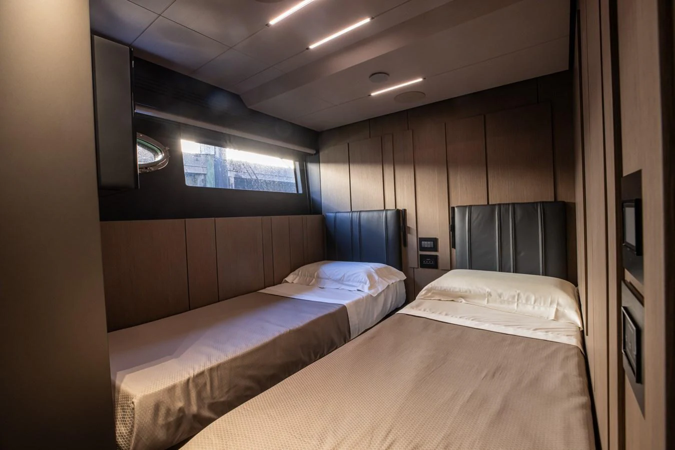 A cozy guest stateroom featuring twin beds and modern lighting. aboard CIAO Yacht for Sale