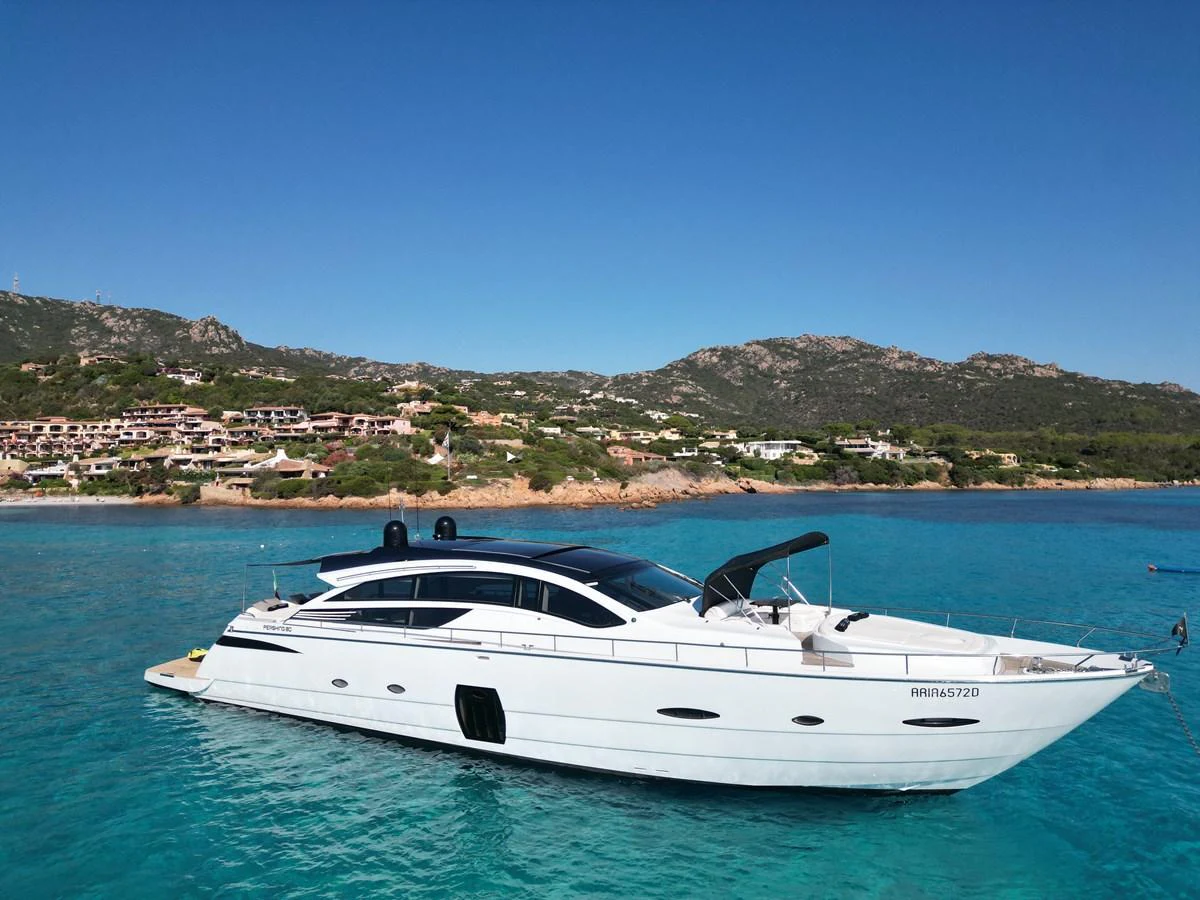 A sleek white yacht cruises through crystal-clear turquoise waters with a scenic coastal backdrop. aboard THYKE III Yacht for Sale