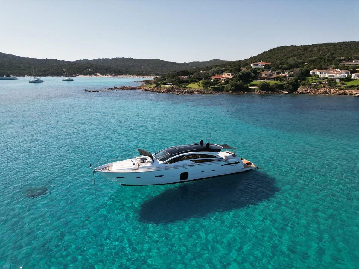 A sleek yacht glides gracefully on crystal-clear turquoise waters near a picturesque coastline. aboard THYKE III Yacht for Sale