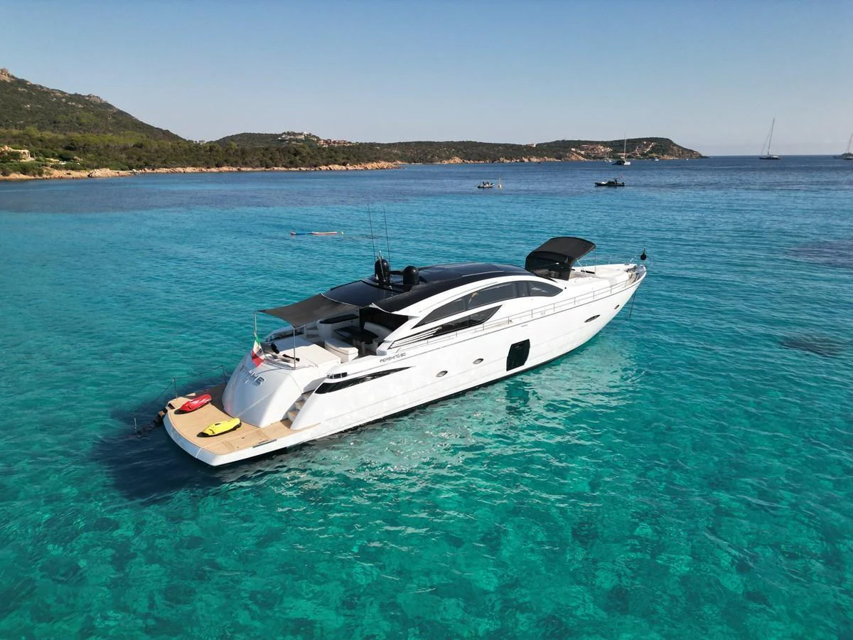 A sleek, modern yacht anchored in crystal-clear turquoise waters near a scenic coastline. aboard THYKE III Yacht for Sale