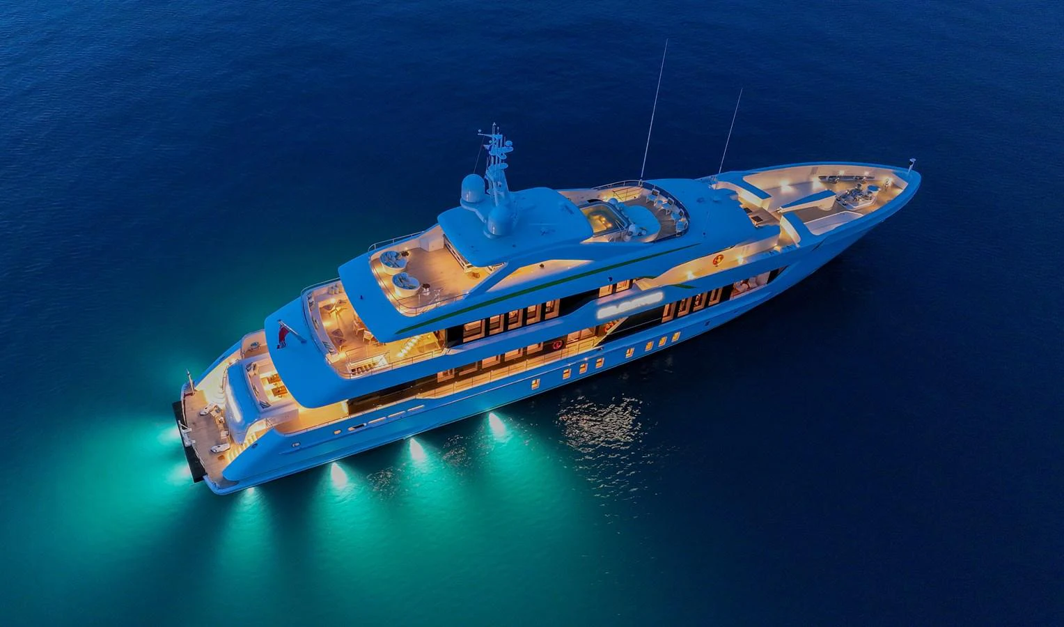 An elegant yacht illuminated beautifully at night, showcasing its luxurious design and spacious decks. aboard SOLEMATES Yacht for Sale