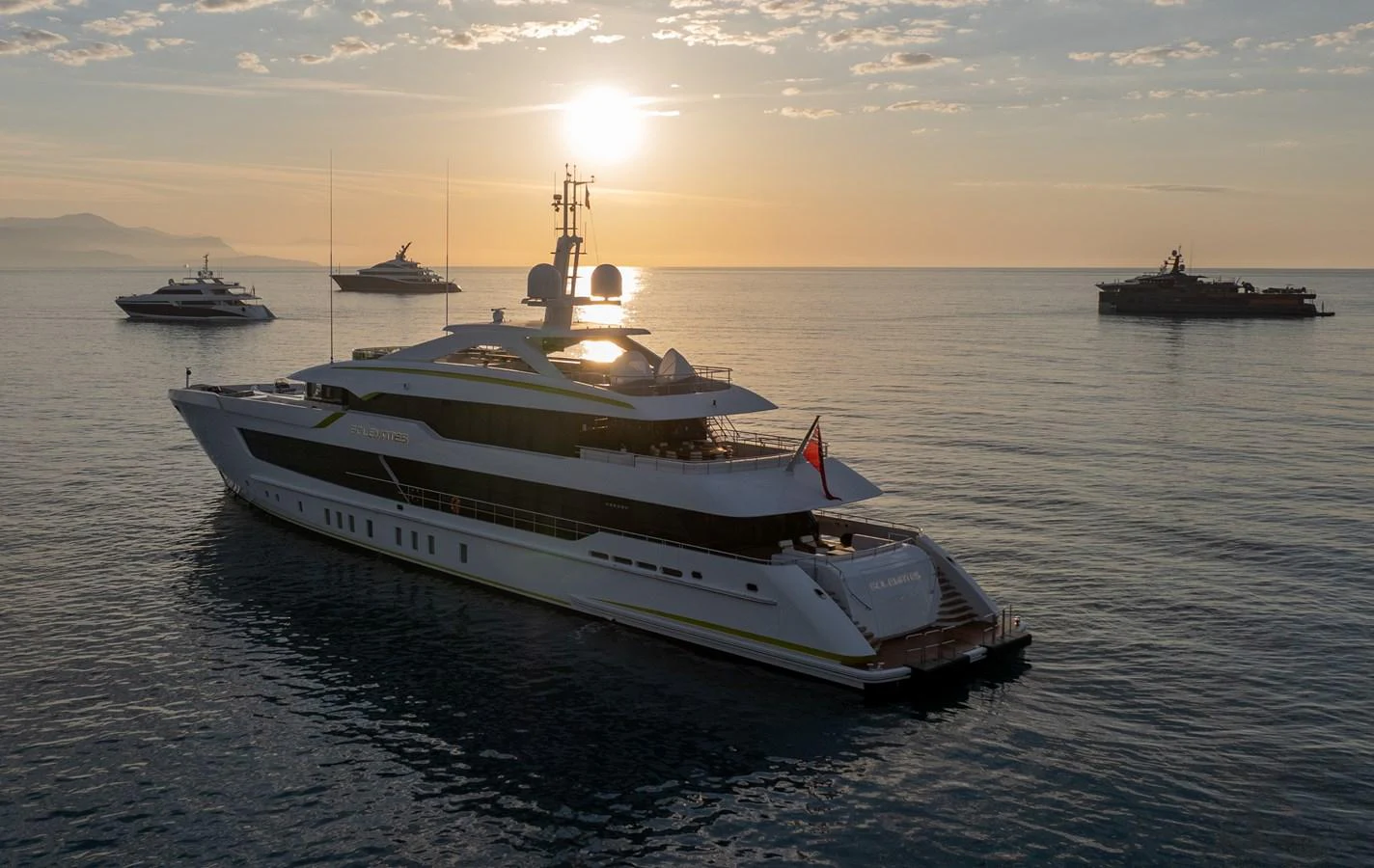 A luxurious yacht glides gracefully on calm waters at sunset, surrounded by other vessels. aboard SOLEMATES Yacht for Sale