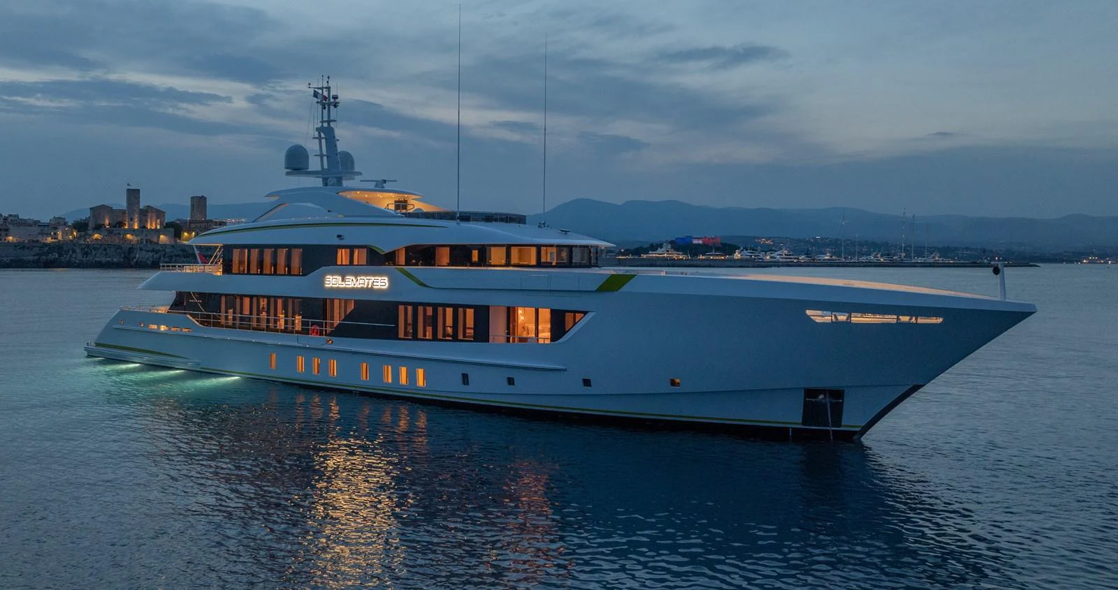 A sleek and modern yacht is illuminated against the twilight backdrop, showcasing its elegant design and luxurious ambiance. aboard SOLEMATES Yacht for Sale