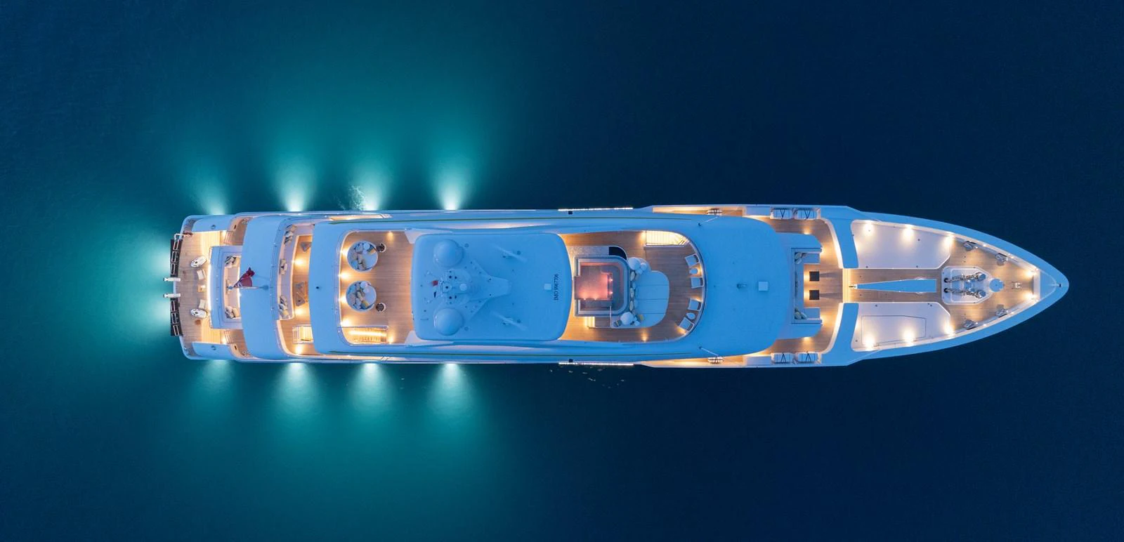 A stunning aerial view of a yacht illuminated beautifully against the dark water. aboard SOLEMATES Yacht for Sale